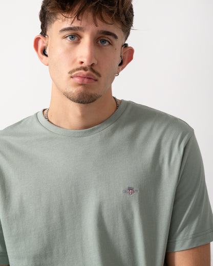Close up shot of a Model wearing a GANT Mens Regular Fit Short Sleeve Shield Logo T-Shirt in Ceramic Grey