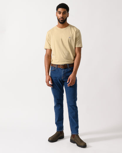 full length shot of a model wearing a GANT Mens Regular Fit Short Sleeve Shield Logo T-Shirt in Oat Beige
