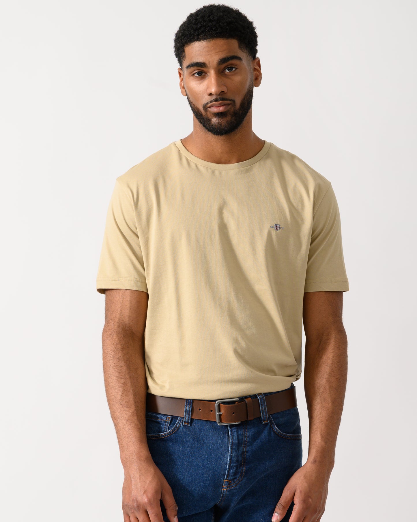 model wearing a GANT Mens Regular Fit Short Sleeve Shield Logo T-Shirt in Oat Beige