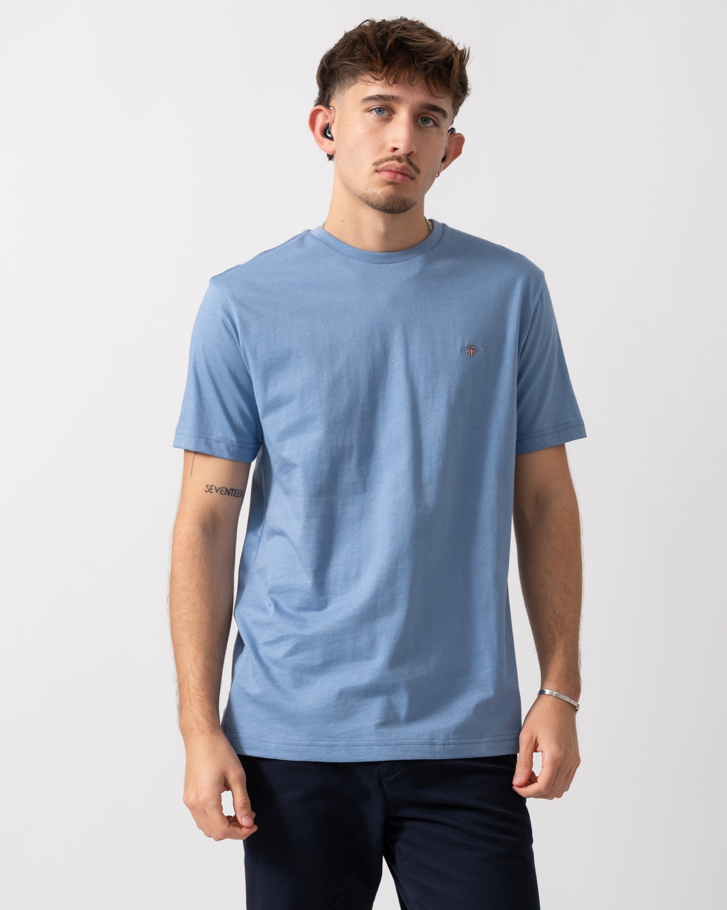 Model wearing a GANT Mens Regular Fit Short Sleeve Shield Logo T-Shirt in Faded Denim