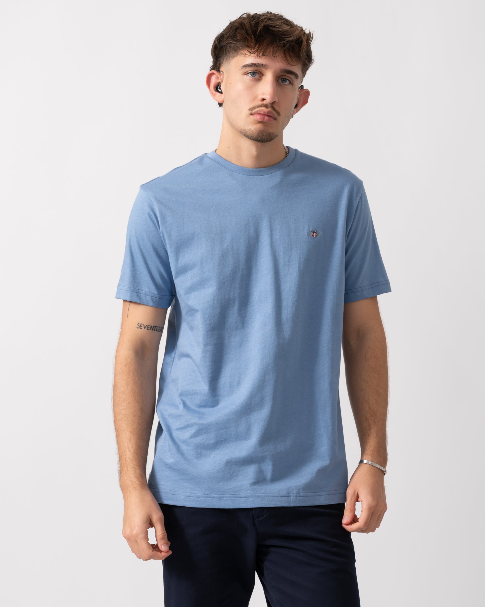 Model wearing a GANT Mens Regular Fit Short Sleeve Shield Logo T-Shirt in Faded Denim