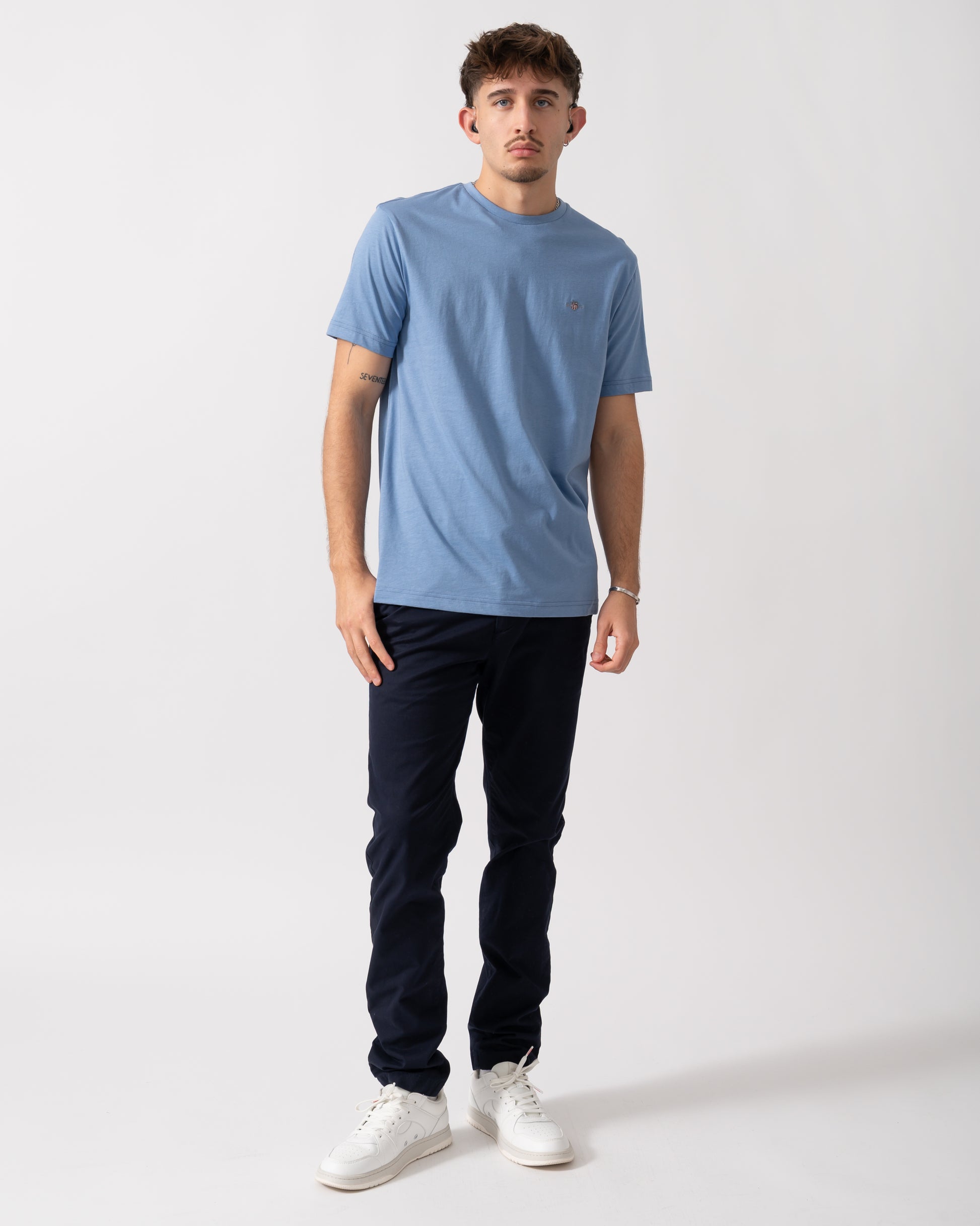 full length of a Model wearing a GANT Mens Regular Fit Short Sleeve Shield Logo T-Shirt in Faded Denim