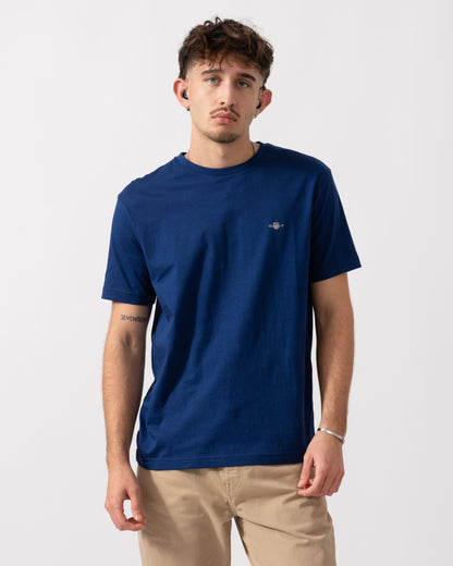 model wearing a GANT Mens Regular Fit Short Sleeve Shield Logo T-Shirt in Rich Navy