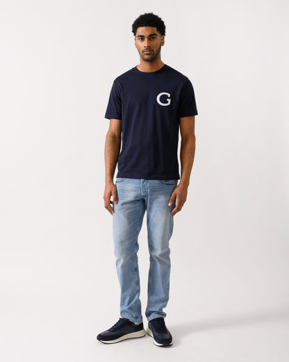 full length shot of aModel wearing a GANT Mens Short Sleeve G-Badge T-Shirt in 433 Evening Blue