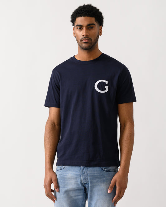 Model wearing a GANT Mens Short Sleeve G-Badge T-Shirt in 433 Evening Blue