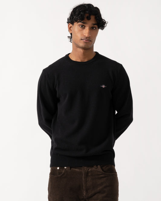 Studio photograph of a model wearing a GANT Mens Superfine Lambswool Crew Neck Sweater in 5 Black