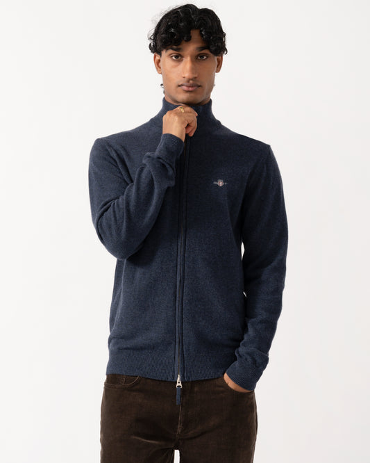 Studio photograph of a model wearing a GANT Mens Superfine Lambswool Full Zip Sweater in 480 Dark Navy Melange