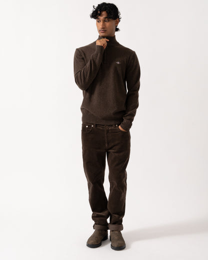 full length studio photograph showing a model wearing a GANT Mens Superfine Lambswool Half Zip Sweater in 280 Dark Brown Melange