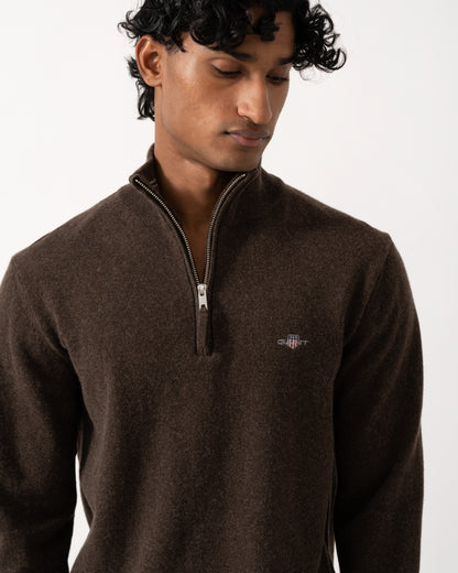 close up studio photograph showing a model wearing a GANT Mens Superfine Lambswool Half Zip Sweater in 280 Dark Brown Melange