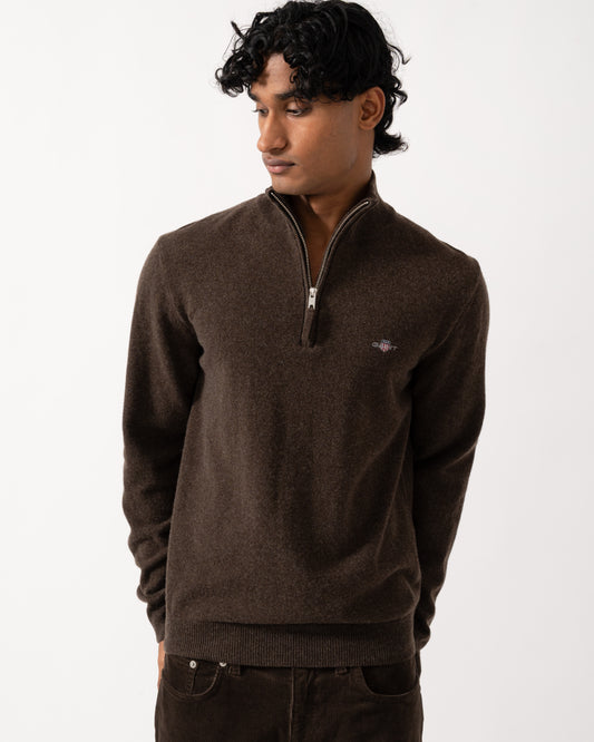 studio photograph showing a model wearing a GANT Mens Superfine Lambswool Half Zip Sweater in 280 Dark Brown Melange