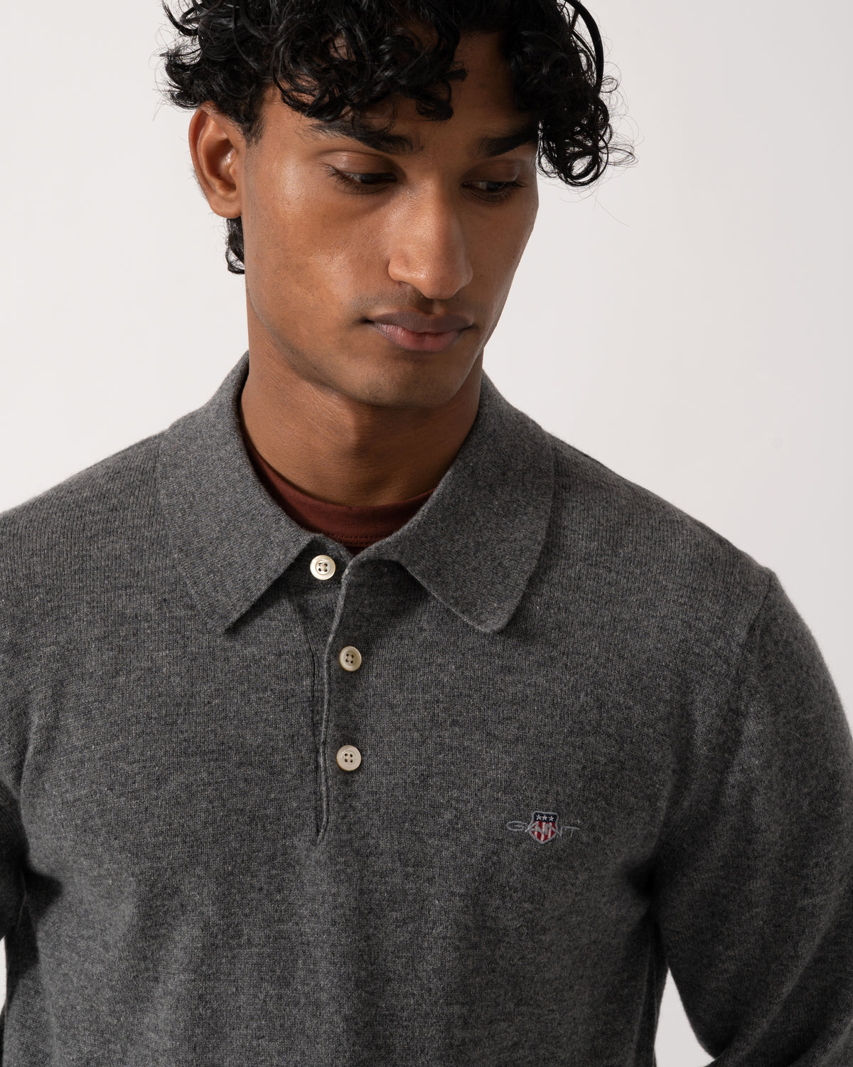 close up Studio photograph of a model wearing a GANT Mens Superfine Lambswool Long Sleeve Polo in 90 Charcoal Melange