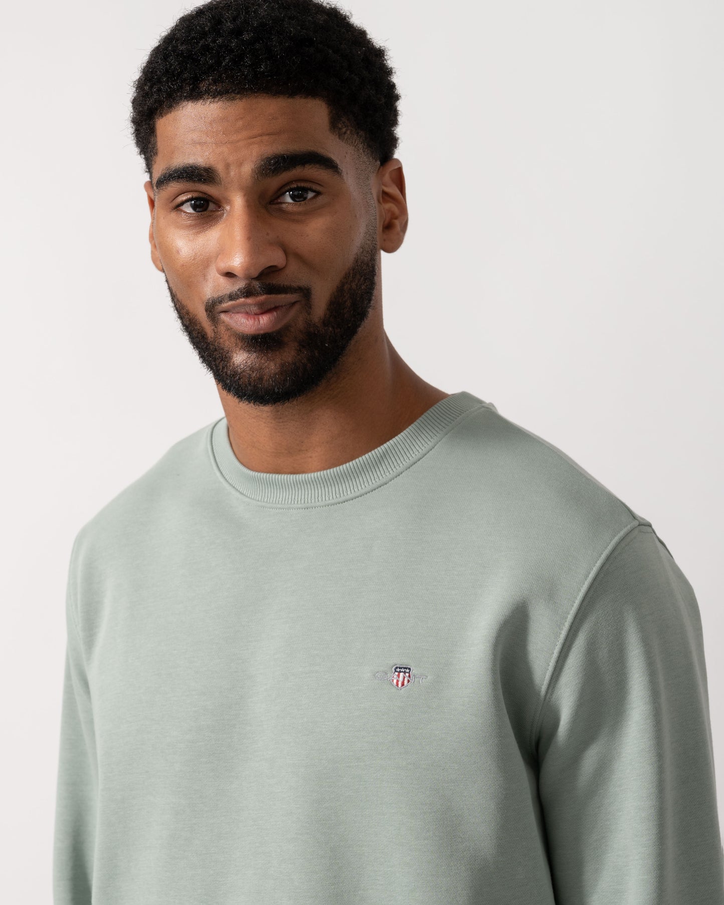 Model wearing GANT Mens Regular Fit Shield Logo Crew Neck Sweatshirt -in 10 Ceramic Grey - detail