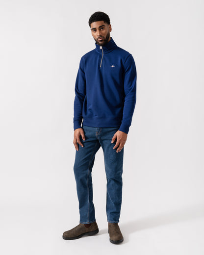 Model wearing GANT Mens Regular Fit Shield Logo Half Zip Sweatshirt in 432 Rich Navy - Full length