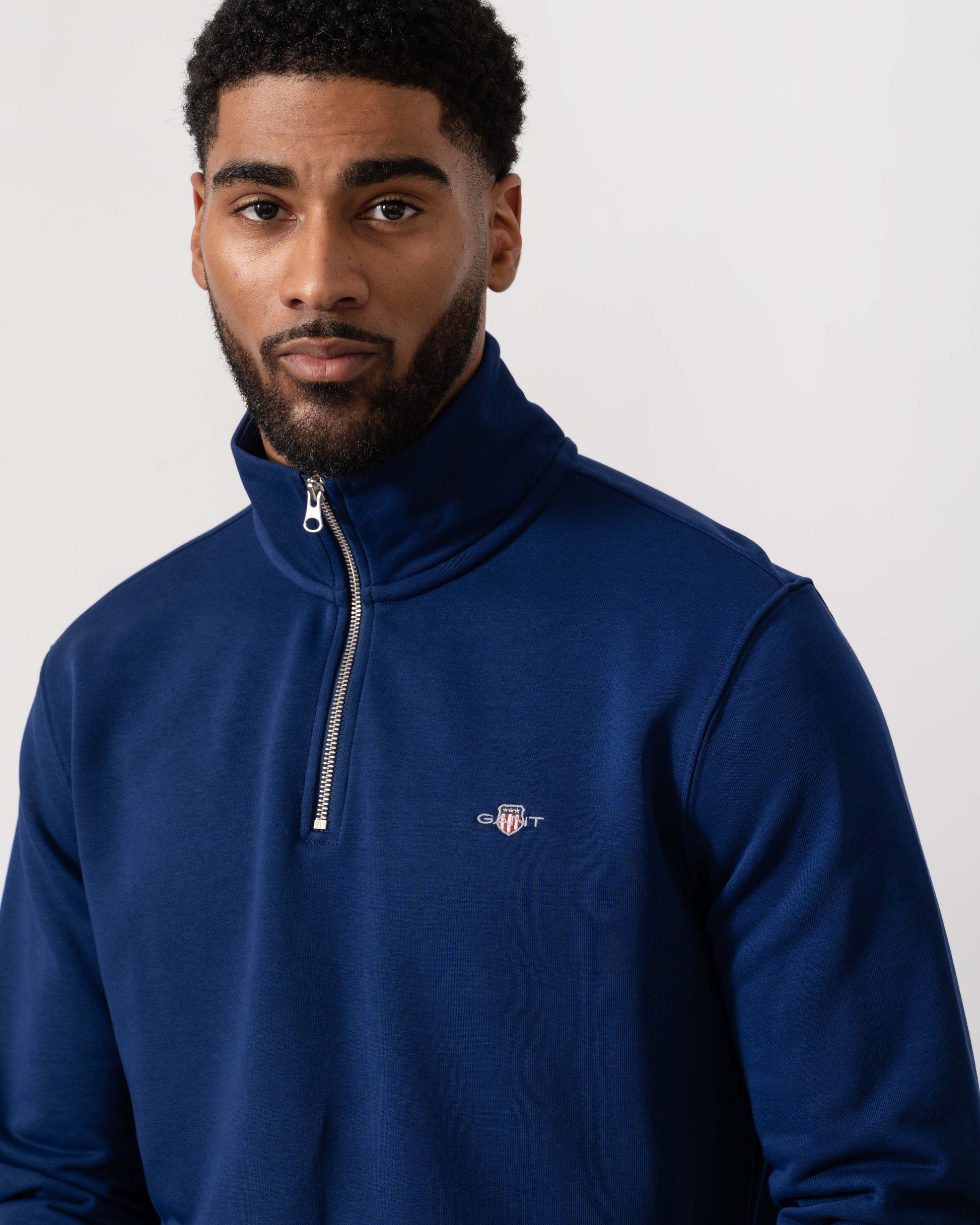 Model wearing GANT Mens Regular Fit Shield Logo Half Zip Sweatshirt in 432 Rich Navy - Detail