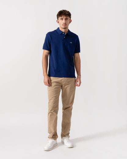 Model wearing GANT Mens Regular Fit Short Sleeve Shield Logo Pique Polo in 432 Rich Navy - Full length
