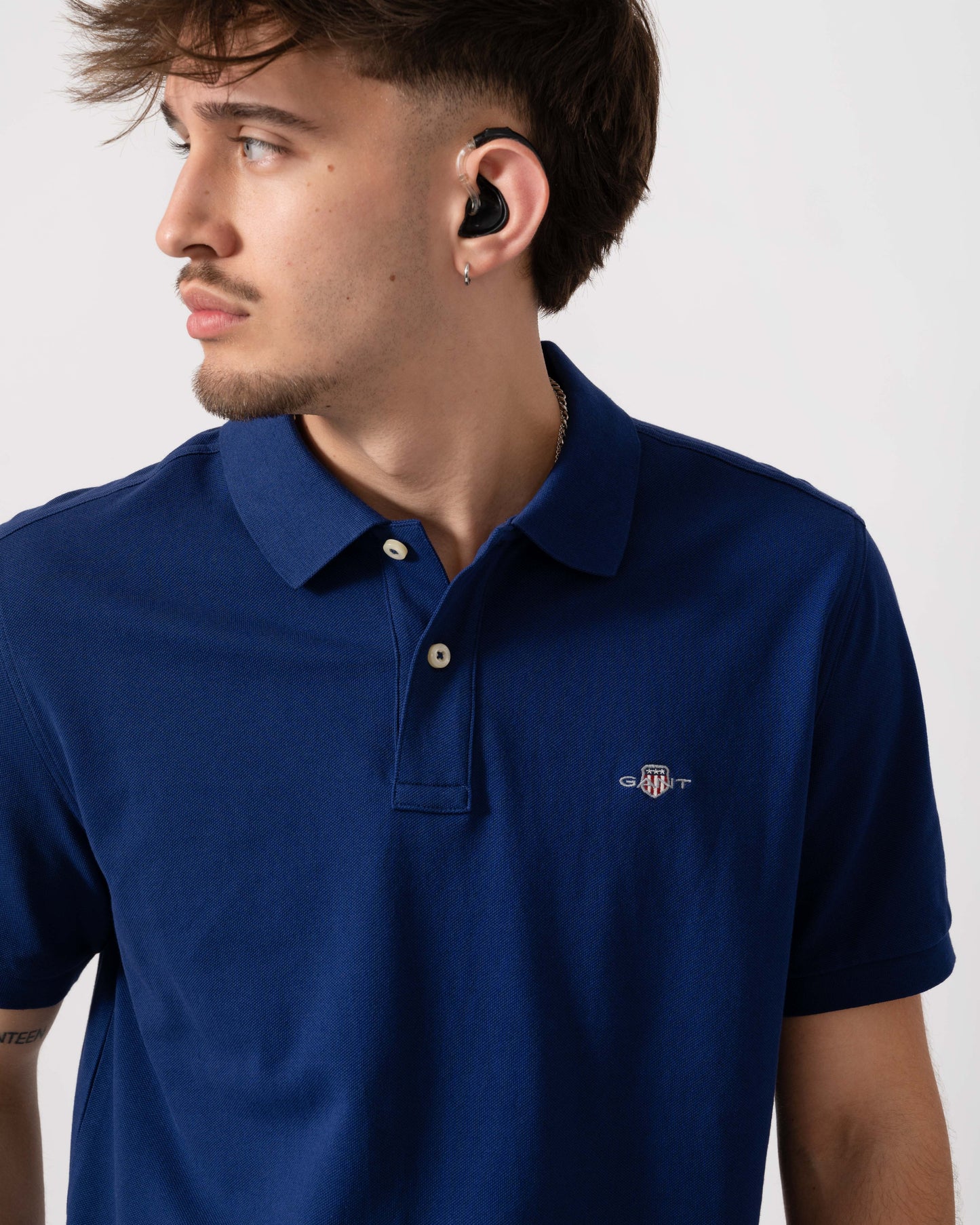 Model wearing GANT Mens Regular Fit Short Sleeve Shield Logo Pique Polo in 432 Rich Navy - Detail