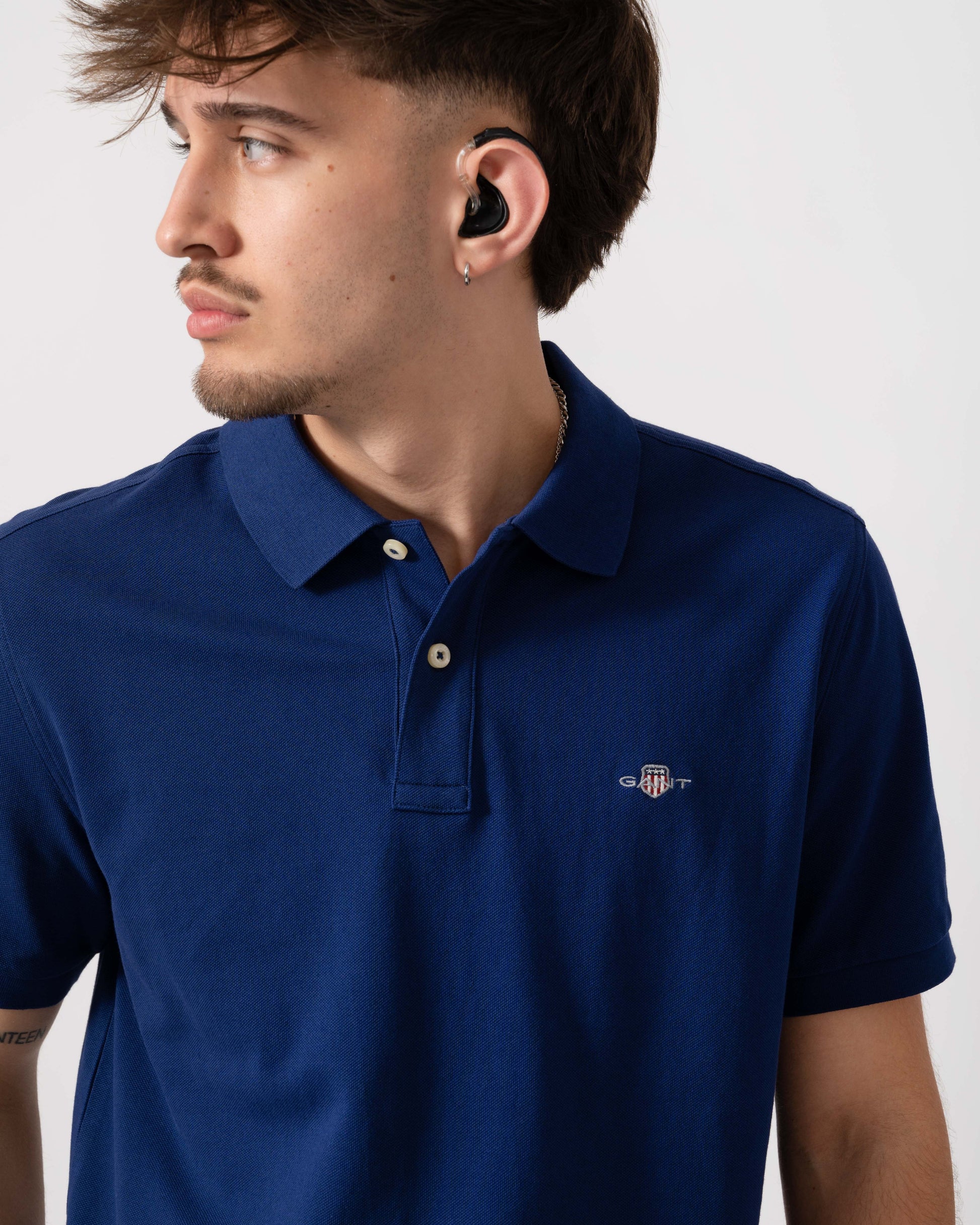 Model wearing GANT Mens Regular Fit Short Sleeve Shield Logo Pique Polo in 432 Rich Navy - Detail