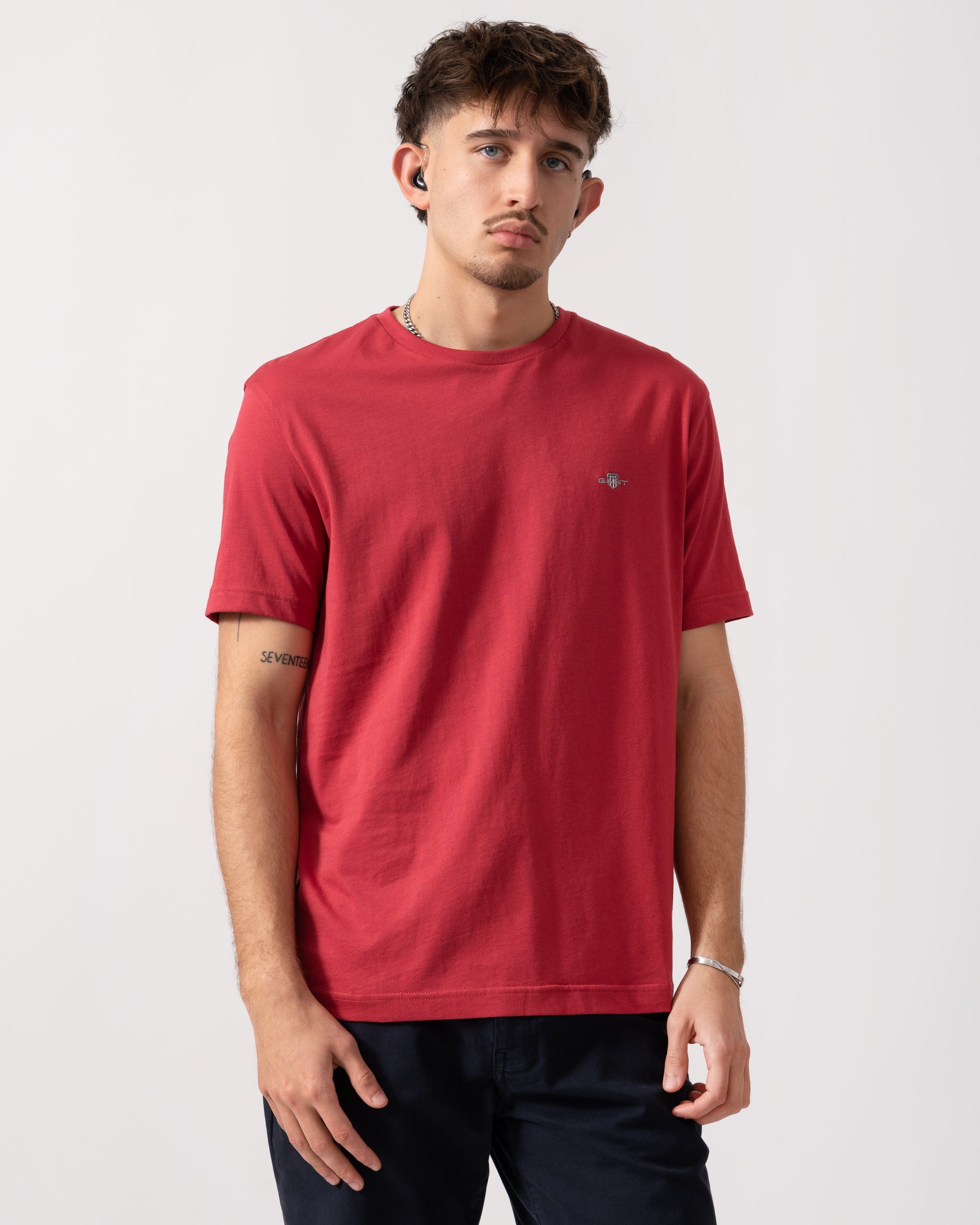 Man wearing a red t-shirt with a small logo on a white background