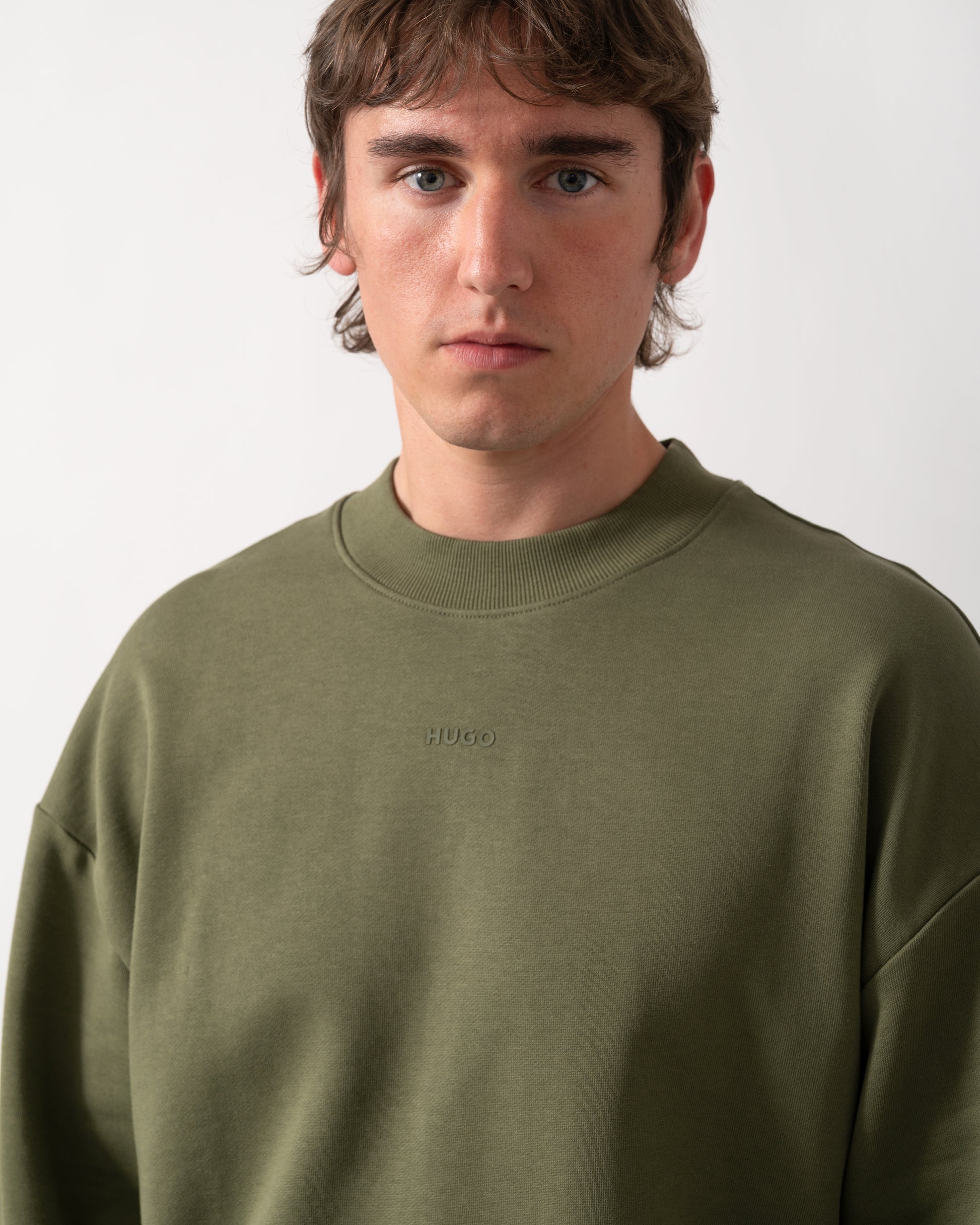 close up  shot of a model wearing a HUGO Dapocrew Mens Crew Neck Sweatshirt in Open Green 388