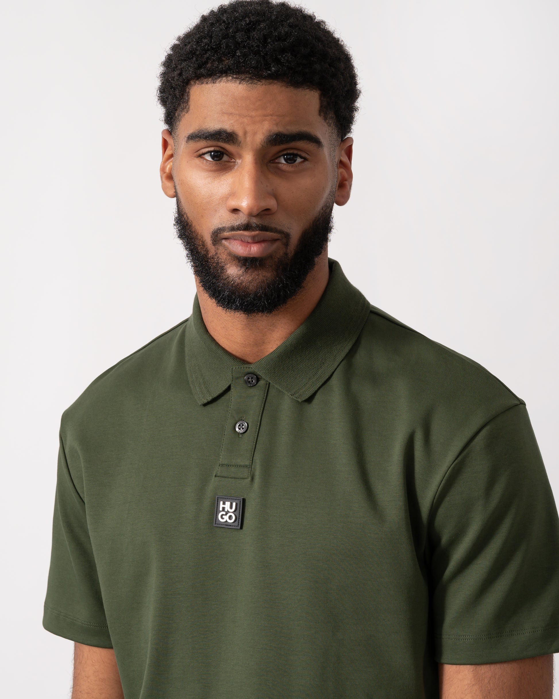 close up of a model wearing a HUGO Deabono Mens Interlock Cotton Polo Shirt with Stacked Logo in Dark Green