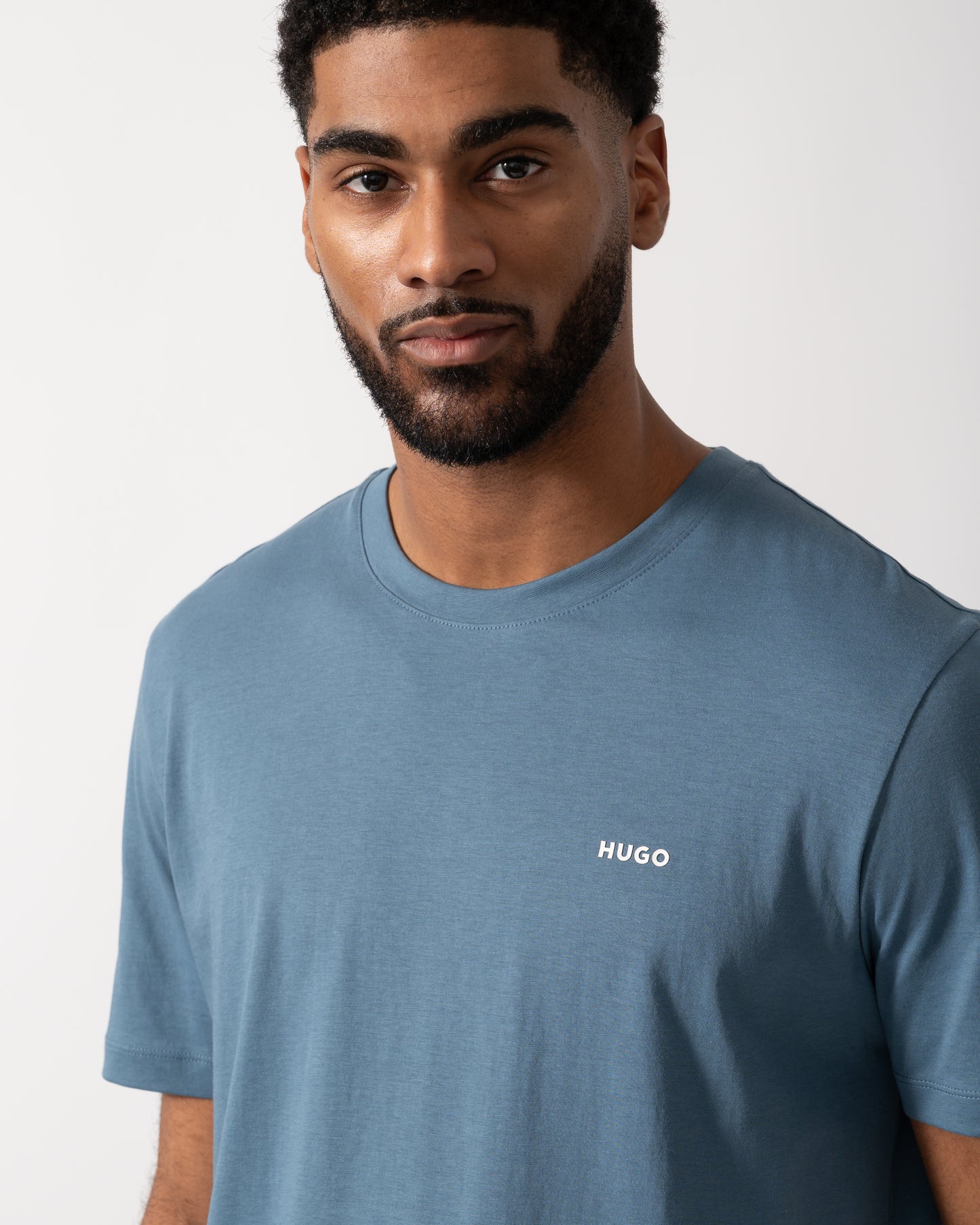 Detail shot of a Model wearing a HUGO Dero222 Mens Cotton-Jersey T-Shirt with Logo Print in Open Blue