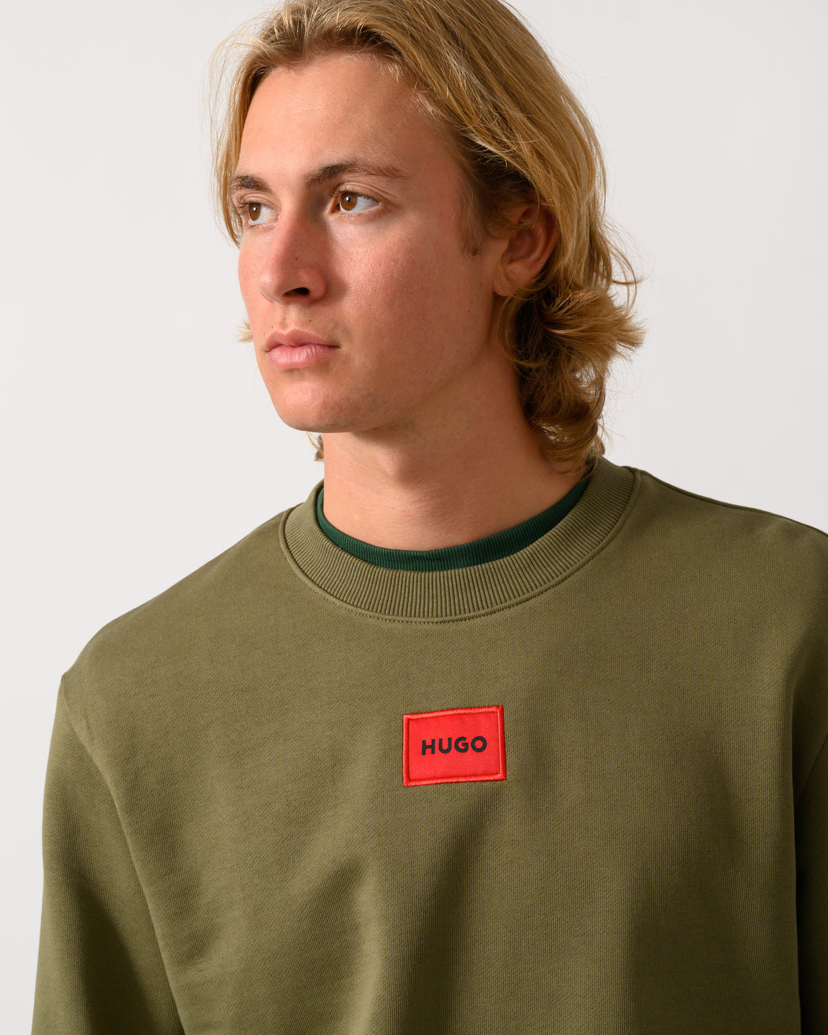 close up of a model wearing a HUGO Diragol212 Label Logo Mens Sweatshirt in Open Green 389