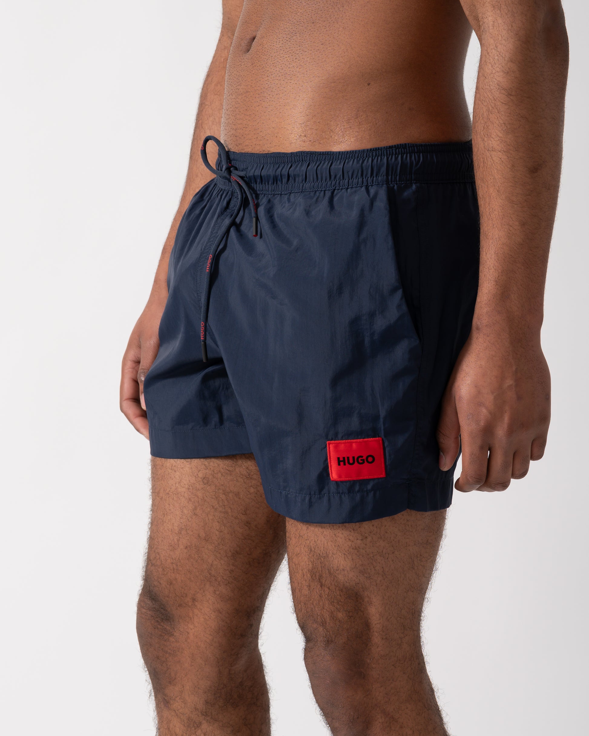 Close up shot of a Model wearing a HUGO Dominica Mens Quick-Drying Swim Shorts In Recycled Material With Logo in Dark Blue