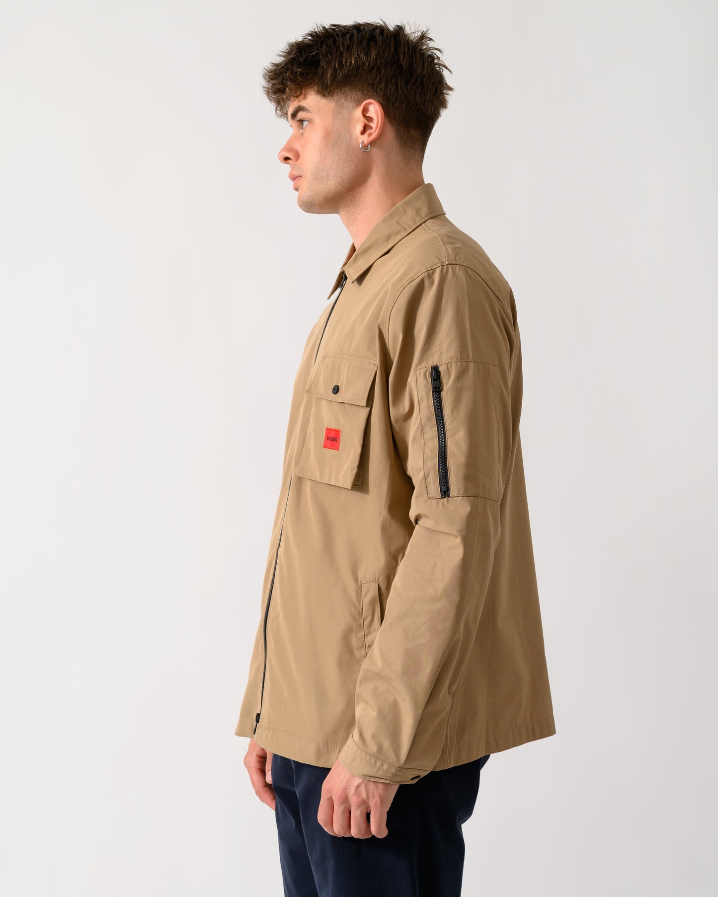 side view of a model wearing a HUGO Emmond Mens Zip Overshirt in Beige Overflow 928