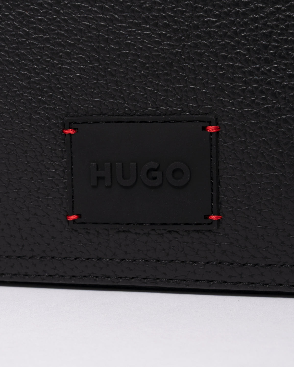 studio photograph showing the logo detail of a HUGO Ethon HI EVO Mens Washbag in Black 002