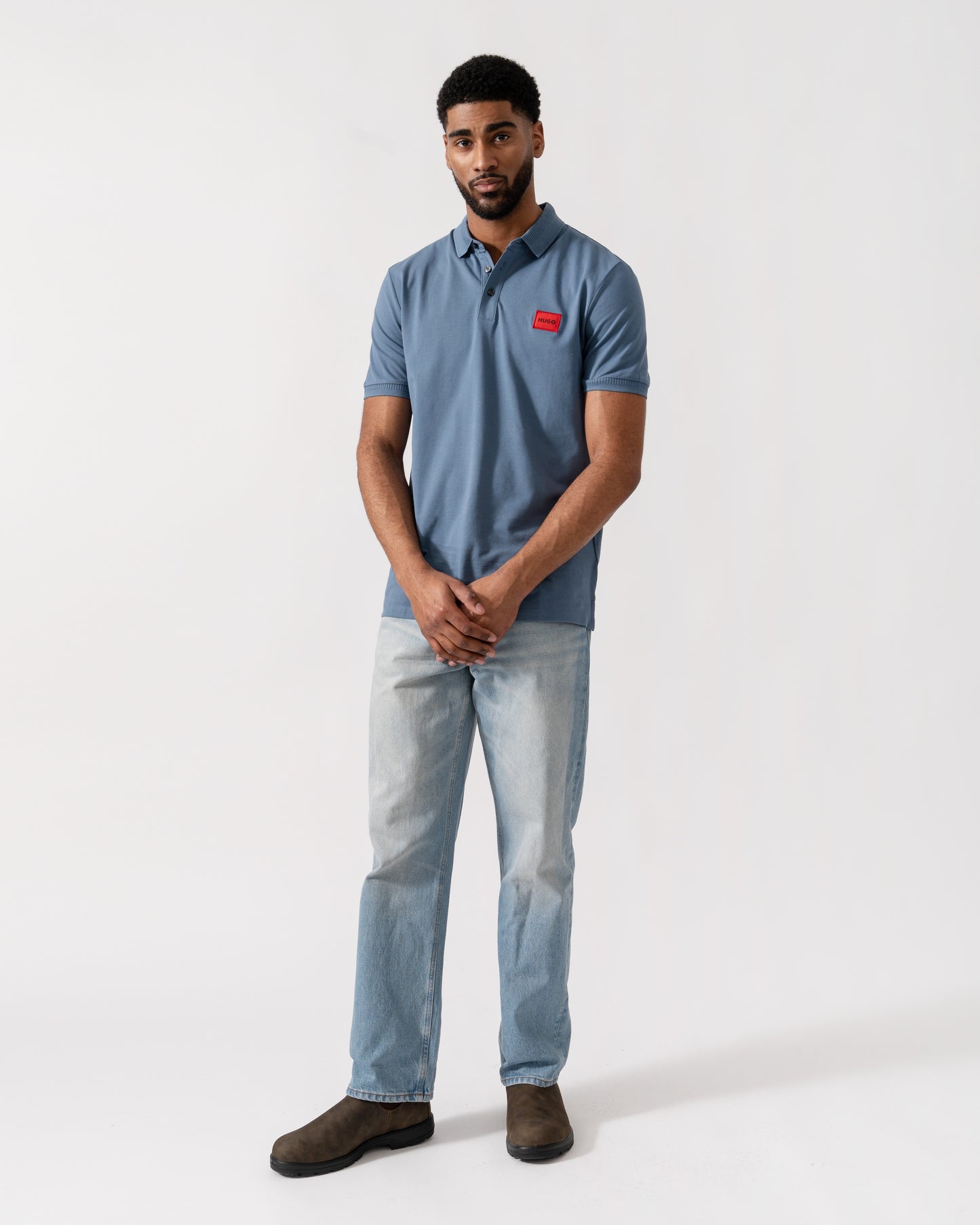 Model wearing HUGO Dereso222 Mens Cotton Piqué Slim-Fit Polo Shirt with Logo Label in Open Blue 496 - Full Length
