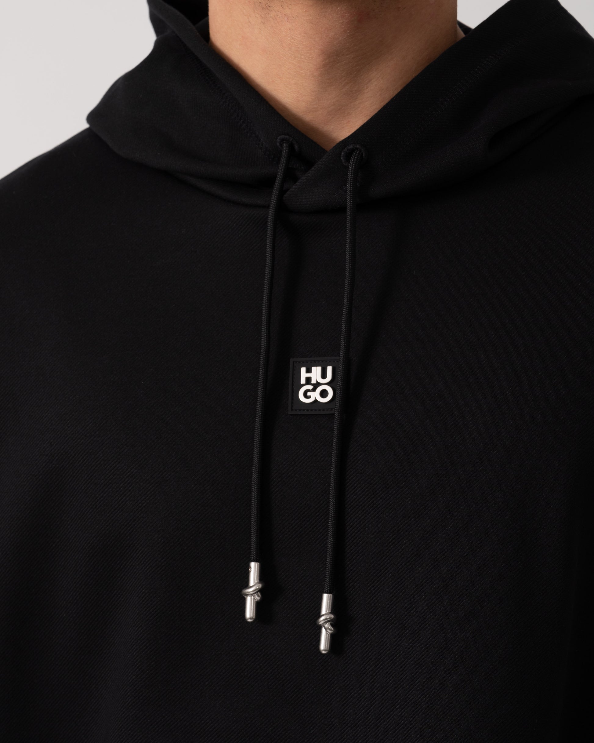 Model wearing HUGO Mens Dineo Mens Pullover Hoodie in Black 001 - Logo detail