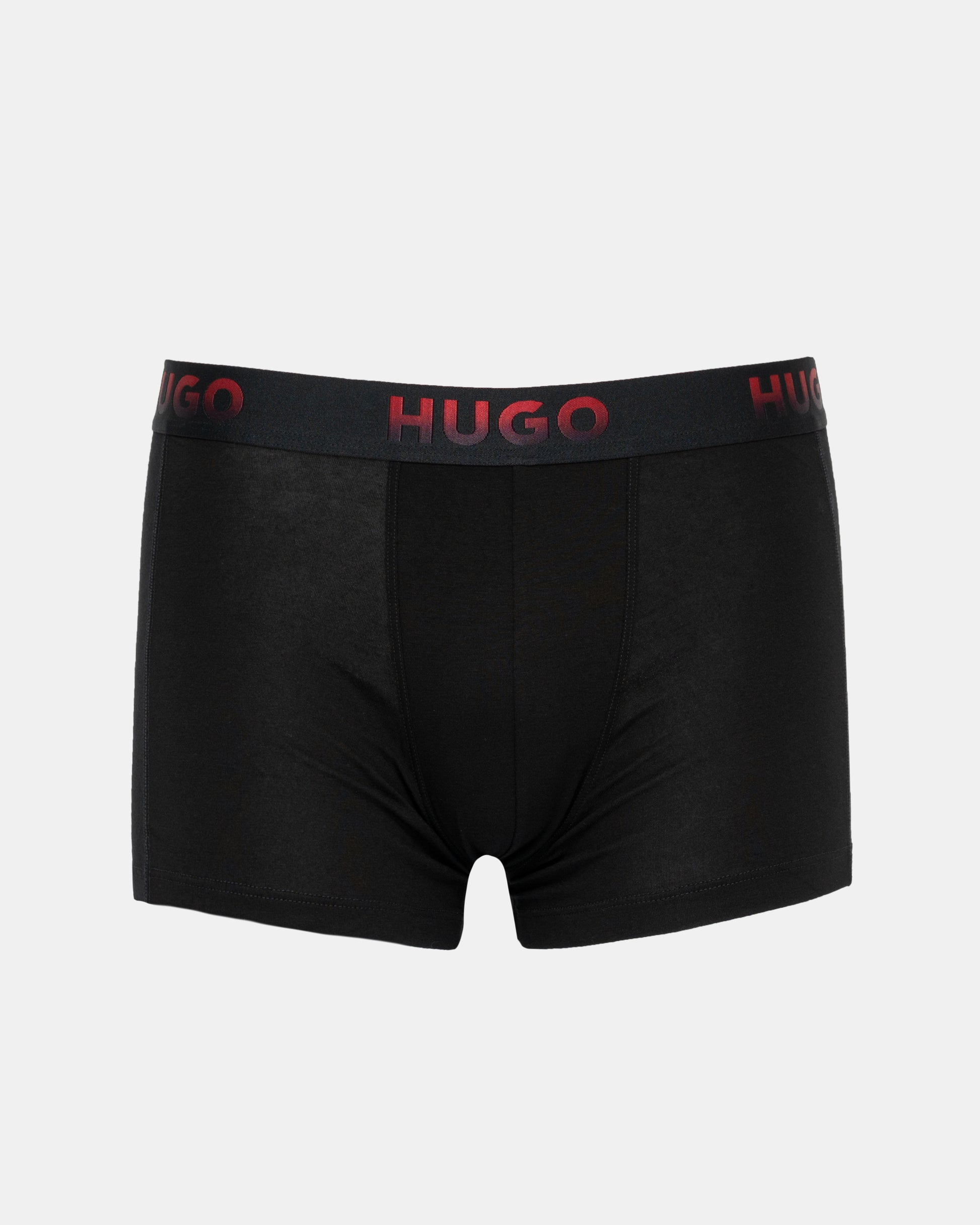 Black boxer briefs with red logo waistband on a light gray background