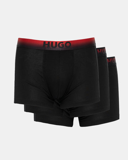 Three black boxer briefs with red waistbands featuring 'HUGO' branding on a light gray background.