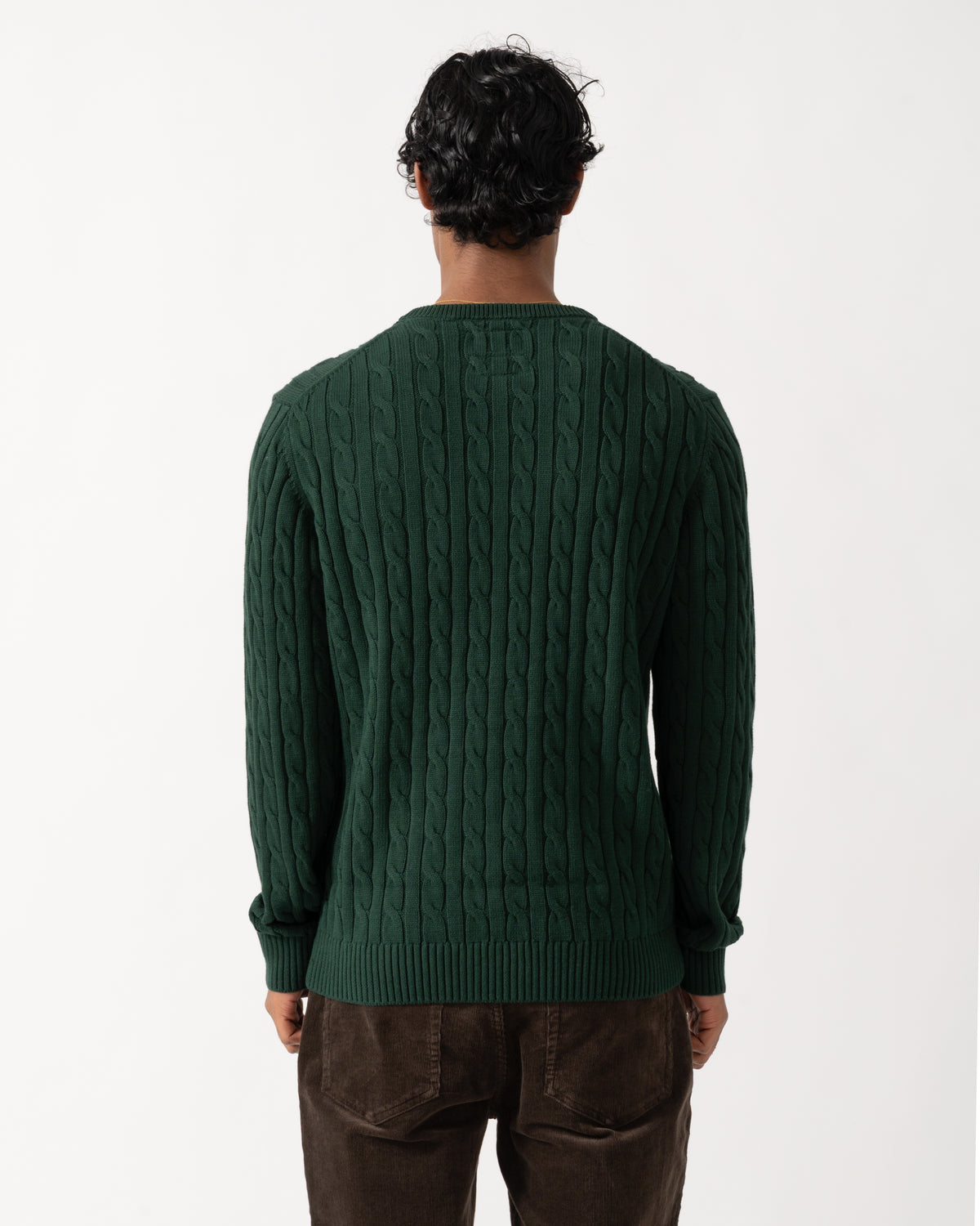 Studio photograph showing the back  of a model wearing a Joules Mens Cable Knit Crew Neck Jumper in Green