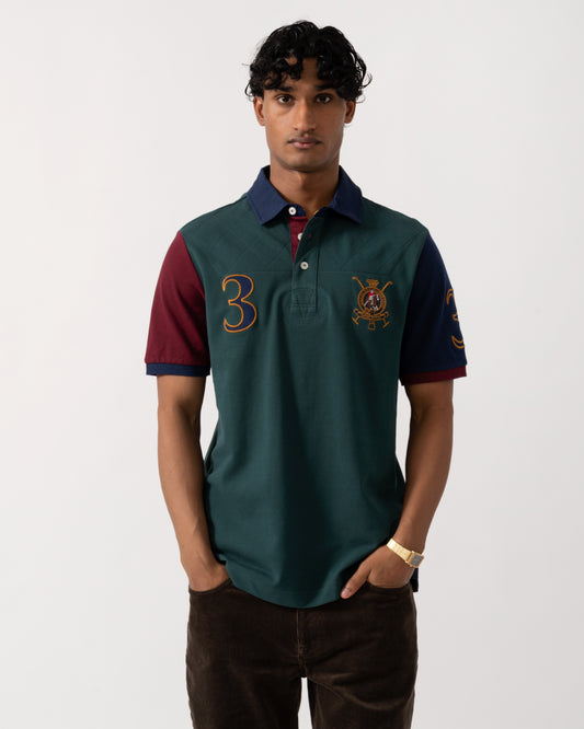 Studio photograph of a model wearing a Joules Woody Mens Embellished Polo Shirt in Green/Burgundy