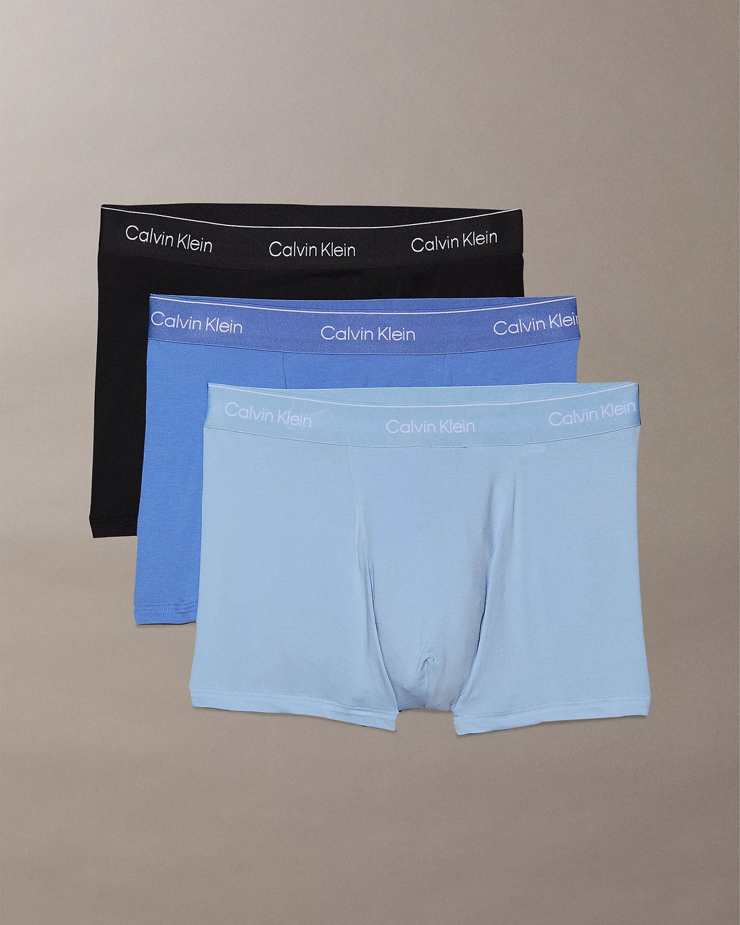 Three pairs of Calvin Klein trunks in black, blue, and light blue.
