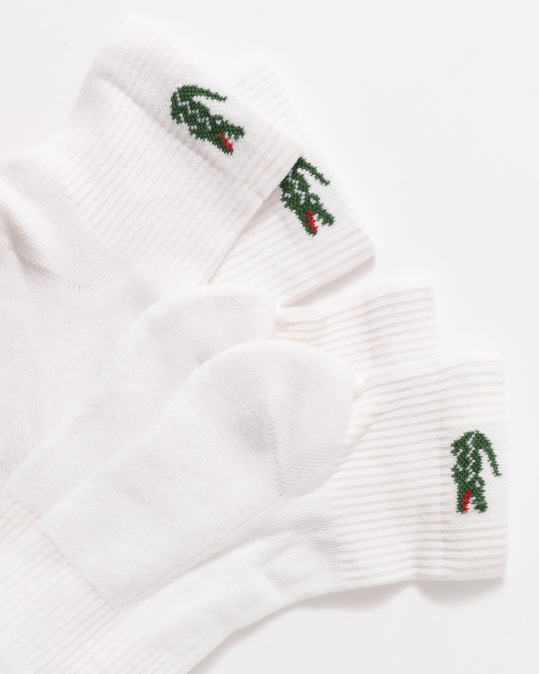 Three white ribbed ankle socks with embroidered green and red alligator motifs on the cuffs, arranged on a clean white background.
