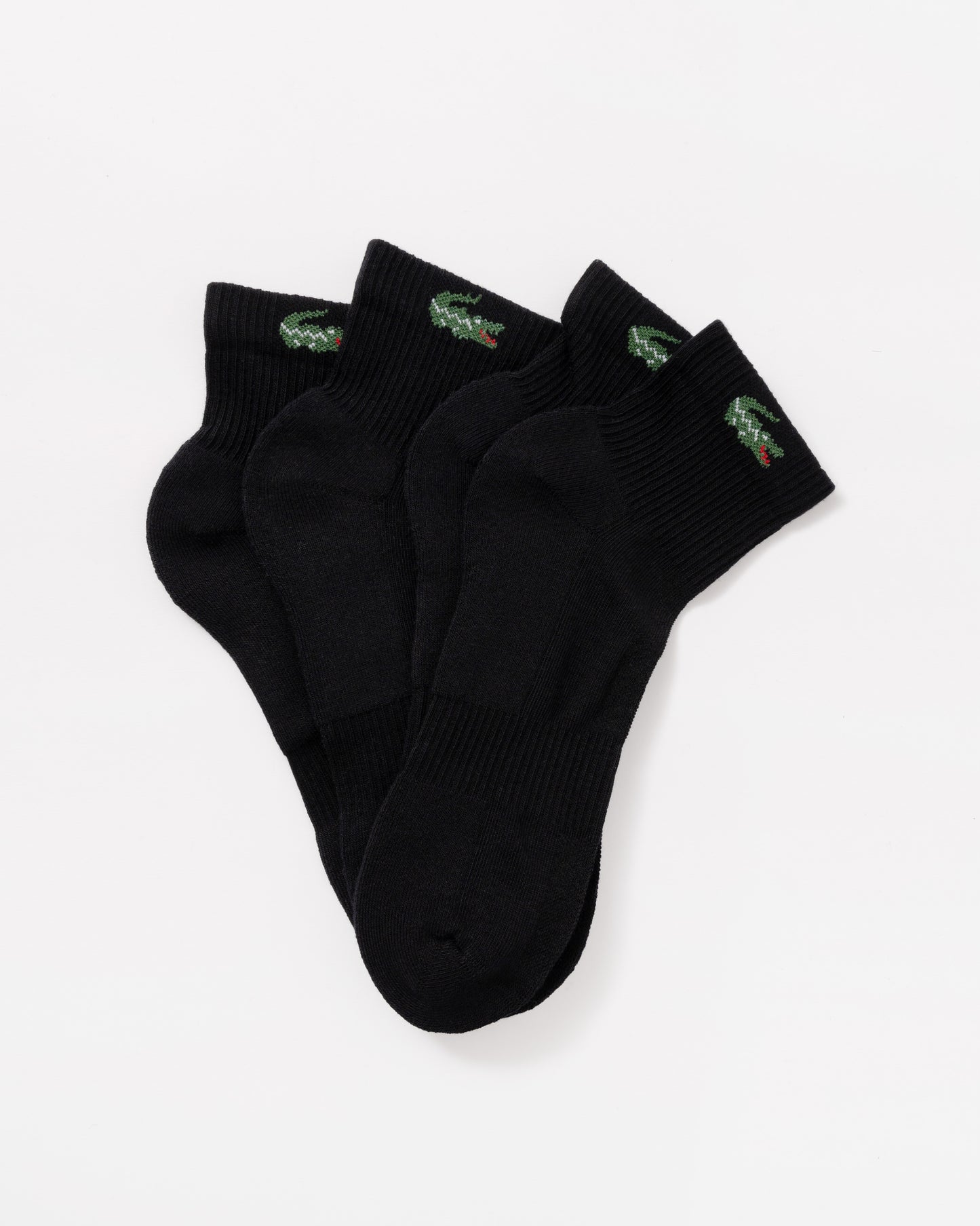 Three black ankle socks with small green and red crocodile logos on the cuffs, arranged in a fan shape on a light gray background.