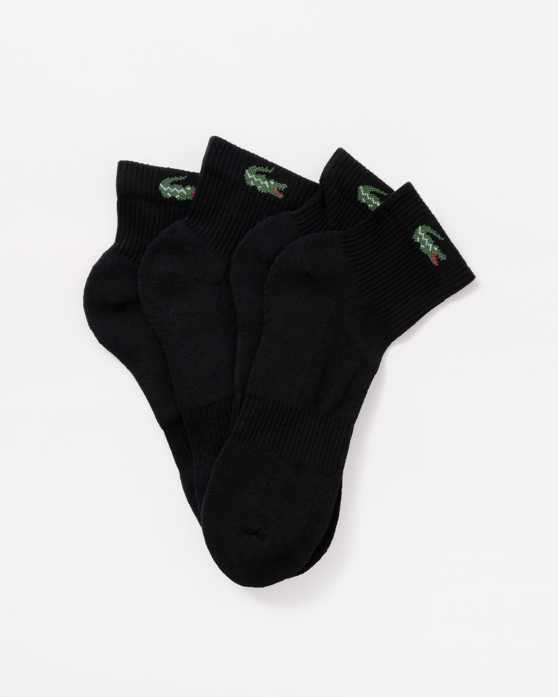 Three black ankle socks with small green and red crocodile logos on the cuffs, arranged in a fan shape on a light gray background.