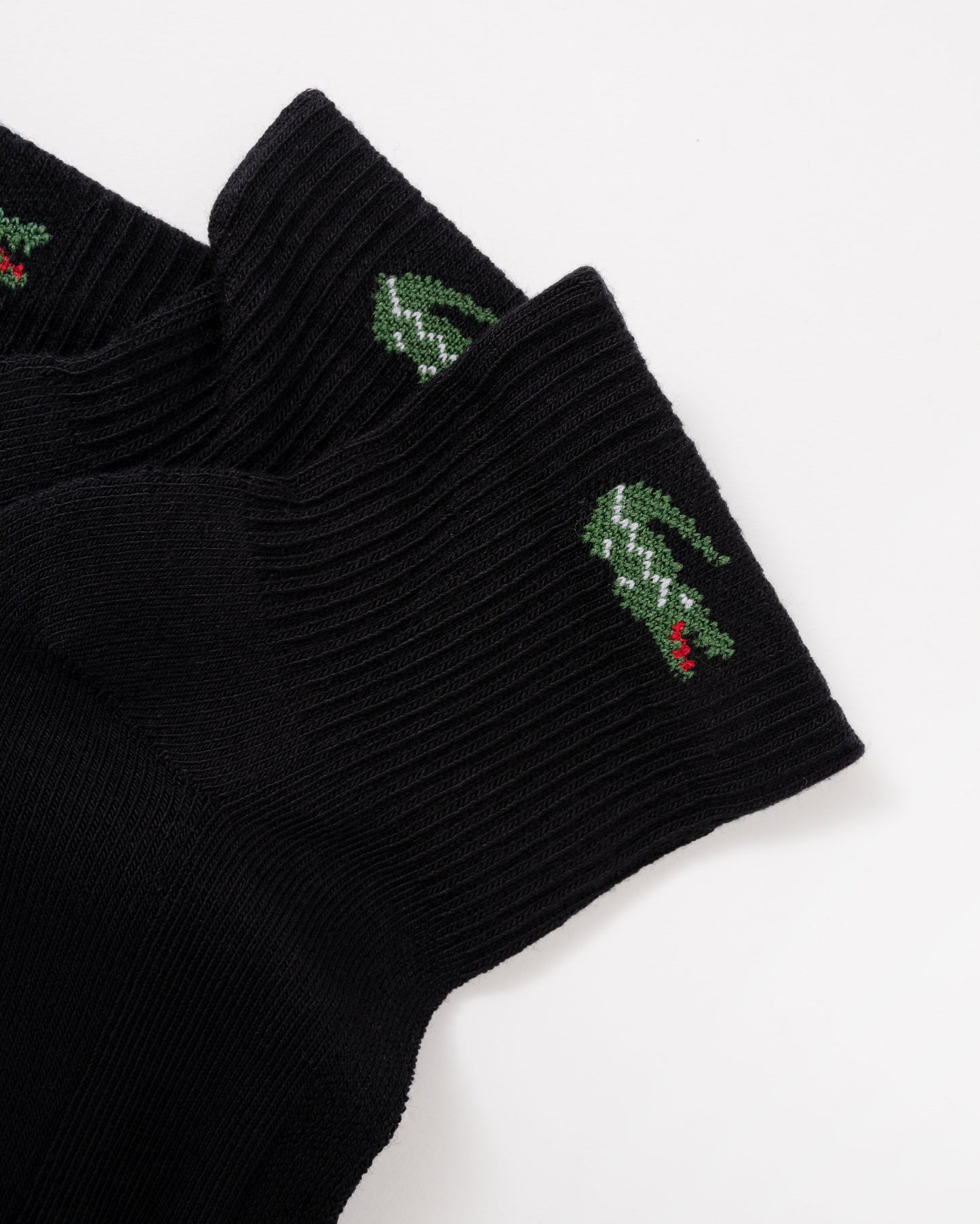 Black ribbed knit socks with green crocodile logos and small red accents on the cuffs, shown on a plain white background.