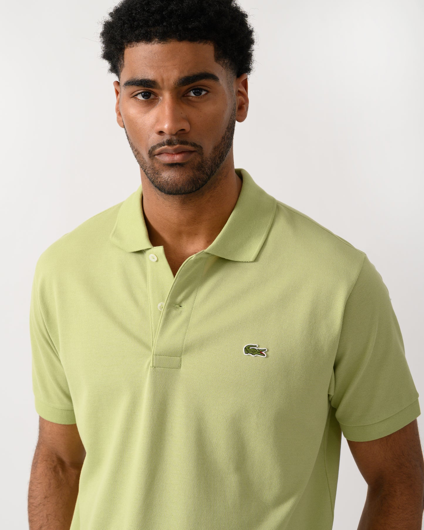 close up shot of a model wearing a Lacoste Classic Fit L.12.12 Mens Short Sleeve Polo Shirt in Birch UYB