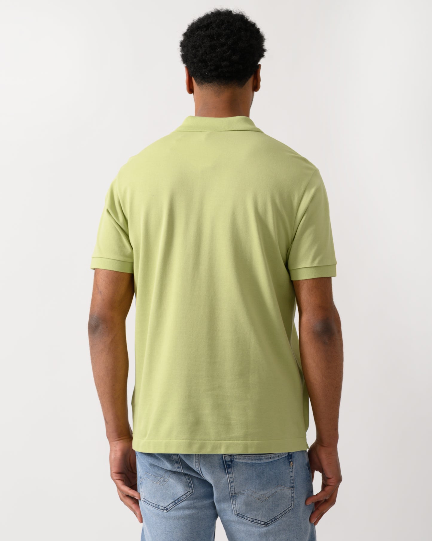 back shot of a model wearing a Lacoste Classic Fit L.12.12 Mens Short Sleeve Polo Shirt in Birch UYB
