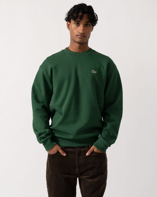 Studio photograph of a model wearing a Lacoste Fleece Mens Classic Fit Sweater in Pine Green 132