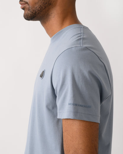 logo shot of a model wearing a Moose Knuckles Crescent Mens T-Shirt in Jet Stream 1884