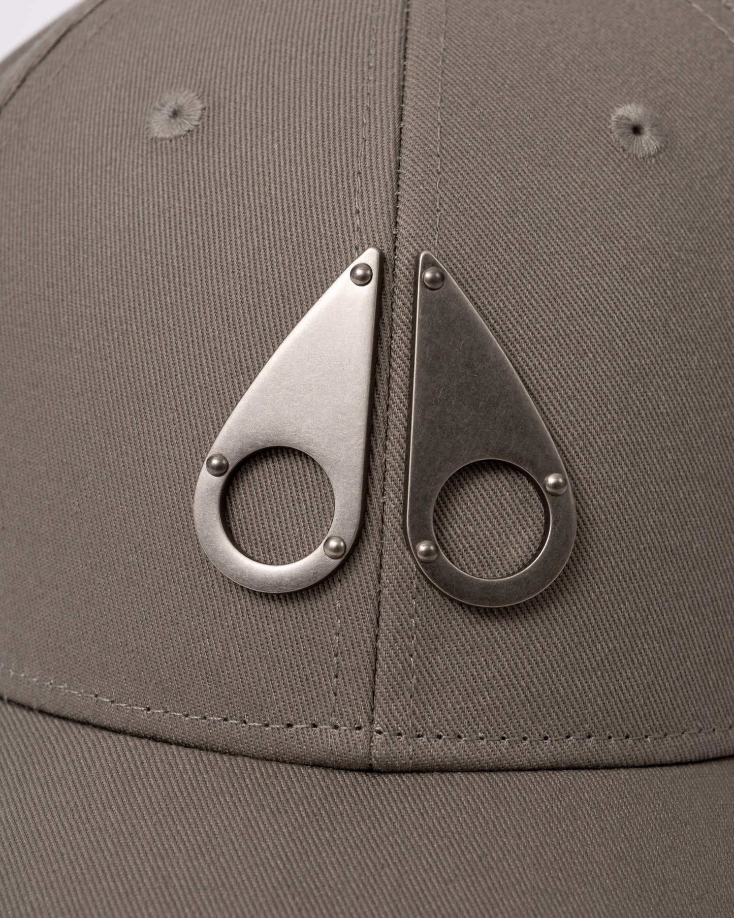 logo detail of a Moose Knuckles Front Logo Icon Cap in Ashen 1968