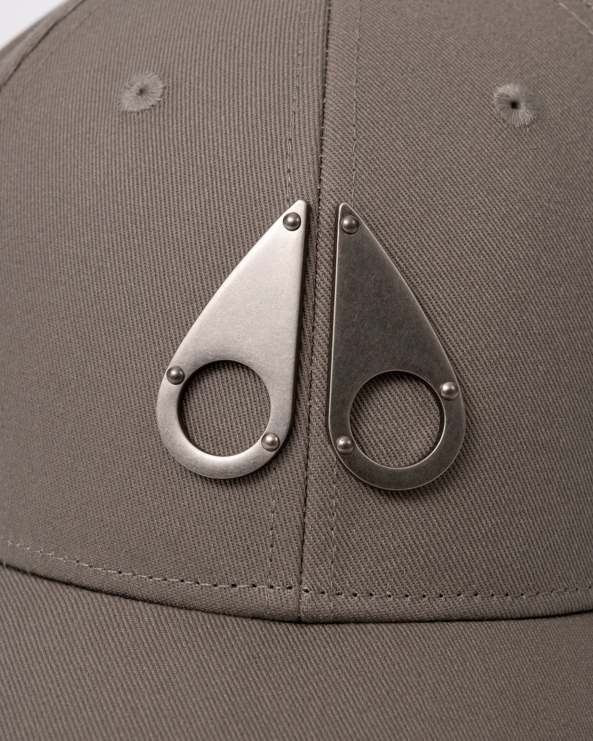 logo detail of a Moose Knuckles Front Logo Icon Cap in Ashen 1968
