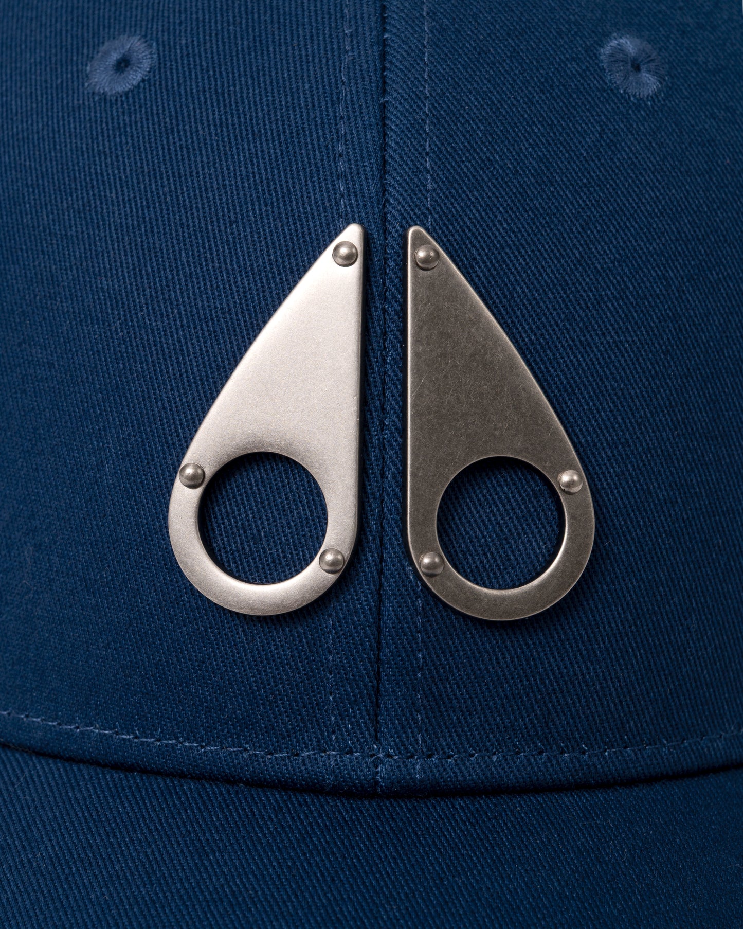 logo detail of a Moose Knuckles Front Logo Icon Cap in Nightfall 1977