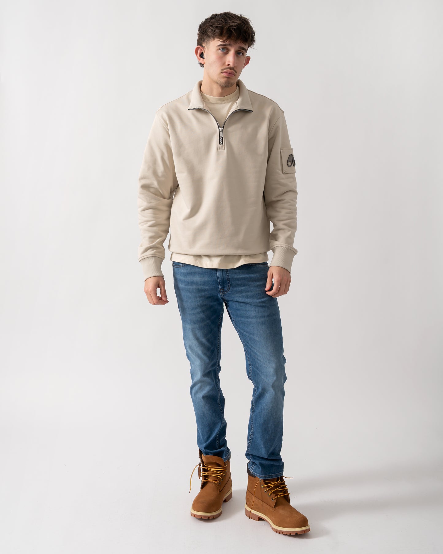 full length shot of a model wearing a Moose Knuckles Hartsfield Mens 1/4 Zip Sweatshirt in Alabaster 1705