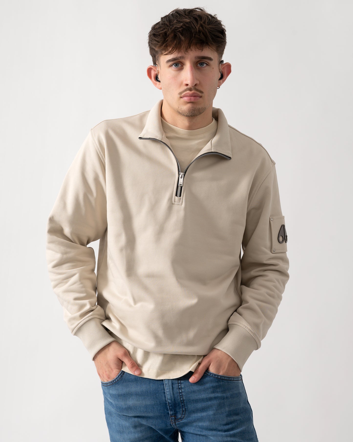 Studio shot of a model wearing a Moose Knuckles Hartsfield Mens 1/4 Zip Sweatshirt in Alabaster 1705