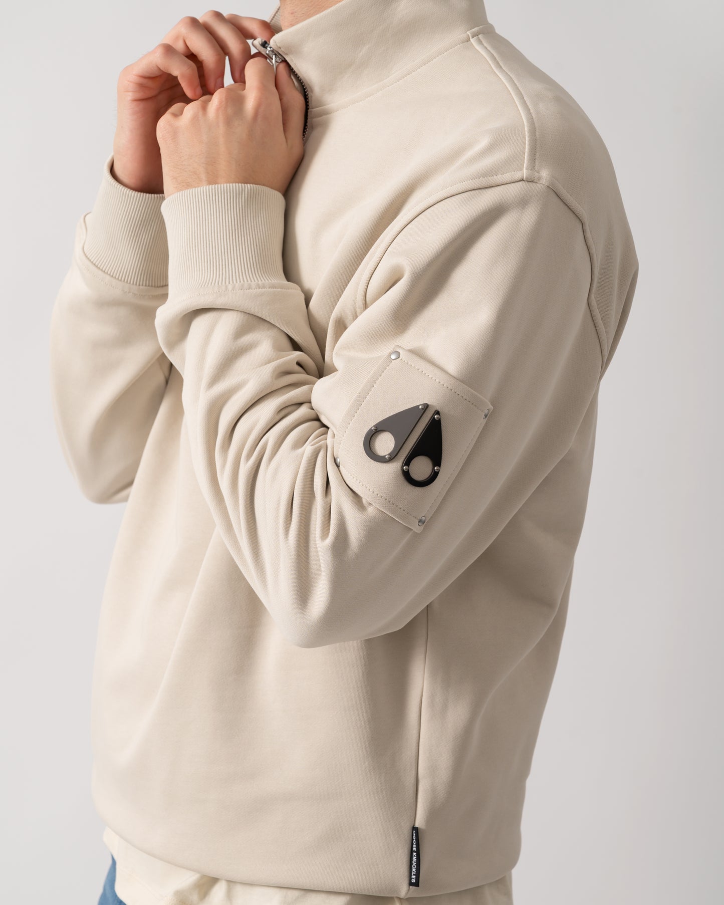 close up shot of a model wearing a Moose Knuckles Hartsfield Mens 1/4 Zip Sweatshirt in Alabaster 1705